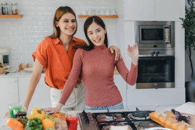 Mutfak odasında kucaklaşan çok ırklı lezbiyen çift. Yüzük tutan siyah beyaz bir çift. Afro-Amerikan ve beyaz lezbiyen çift birbirlerine şefkatle sarılıp bakıyorlar.