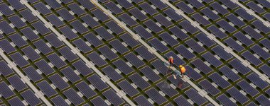 Göl üzerinde yüzen güneş panelleri ya da güneş pili platformu sistemini fırça ve suyla temizleyen işçiler. Bir güneş enerjisi santralinde güneş modüllerini temizleyen işçiler