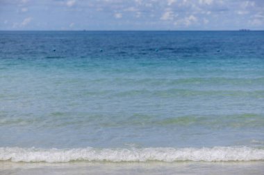 Kumlu sahilde yumuşak bir okyanus dalgası. Kumsalda deniz dalgası. Beyaz kumsal ve mavi gökyüzü.