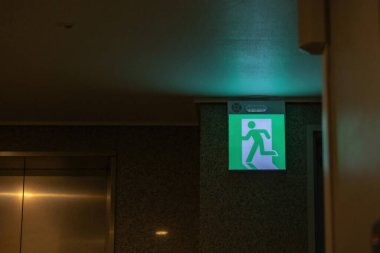 Kaçış yolunu gösteren yeşil acil çıkış işareti. Binadaki yangın çıkışı..