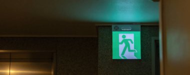 Kaçış yolunu gösteren yeşil acil çıkış işareti. Binadaki yangın çıkışı..