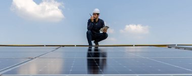Fabrikanın çatısındaki güneş pilini kontrol et. Çatıda yürüyen mühendisler güneş pili panelini inceleyip kontrol ediyorlar. Çatıda çalışan mühendis teftiş kurulum güneş hücresi