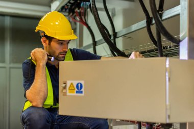 Kontrol odasında çalışan elektrik mühendisi. Elektrik mühendisi kontrol odasındaki güç dağıtım dolabını kontrol ediyor.