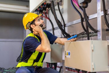 Kontrol odasında çalışan elektrik mühendisi. Elektrik mühendisi kontrol odasındaki güç dağıtım dolabını kontrol ediyor.