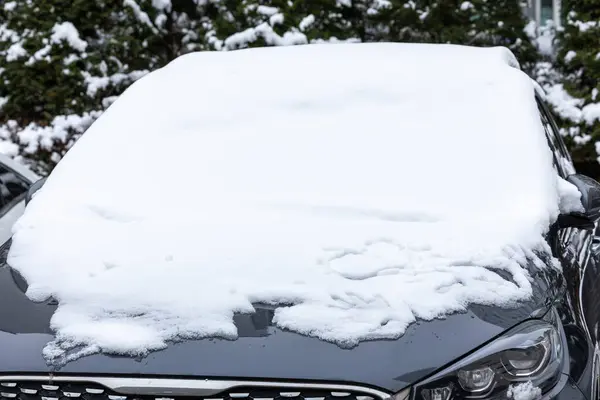 Winter frozen back car window, texture freezing ice glass background. Frozen car covered snow at winter day, view front window windshield and hood on snowy background