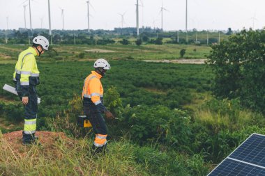 Tarım arazisindeki güneş panellerini kontrol eden mühendis. Olay yerinde güneş panellerini inceleyen mühendis. Teknisyenler tarım alanındaki güneş enerjili voltaik panelleri tamir ediyorlar. temiz enerji