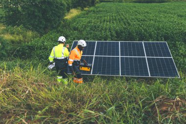 Tarım arazisindeki güneş panellerini kontrol eden mühendis. Olay yerinde güneş panellerini inceleyen mühendis. Teknisyenler tarım alanındaki güneş enerjili voltaik panelleri tamir ediyorlar. temiz enerji