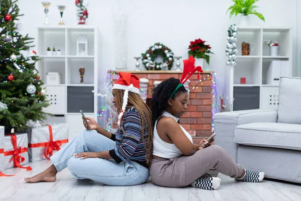 Двоє Друзів Африки Сидять Вітальні Дивляться Смартфони Різдвяні Прикраси Вітальні — стокове фото