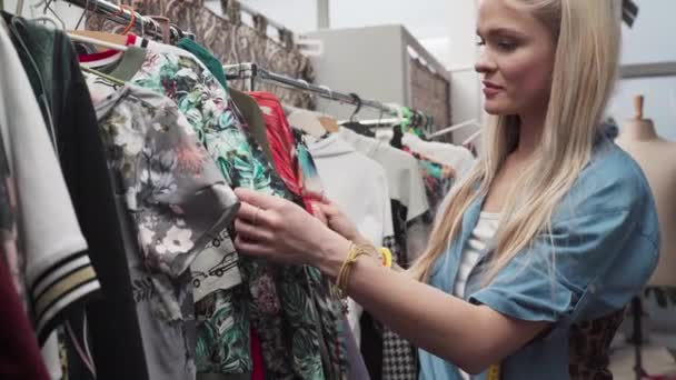 Ένα Κορίτσι Ξεφυλλίζει Ρούχα Από Νέα Συλλογή Ενός Γνωστού Σχεδιαστή — Αρχείο Βίντεο
