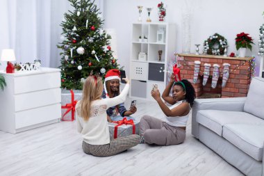 Üç bakire Noel 'i birlikte kutluyor. Akıllı bir telefonla neşeli fotoğraflar çekildi. Selfie, selfie ve sosyal medya için bir hatıra..