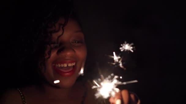 寒い火災で新年の喜びと楽しさ 炎の火花に照らされた暗い肌のアフリカ人女性の顔を手に持っている — ストック動画