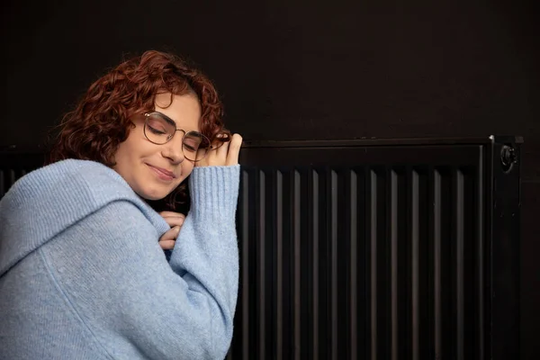 Satisfied Girl Smiles Hugs Hot Radiator Closed Eyes Woman Curly — Stock Photo, Image