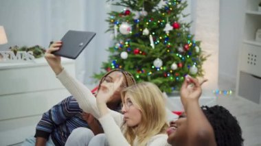 Afrikalı kadınlar ve Avrupalı bir kadın tüm aile için selfie çekiyor. Uluslararası Noel. Gülümseyen ve mutlu kızlar.