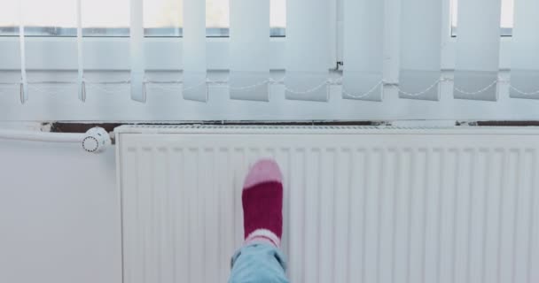 一个人把冻僵的脚靠在炽热的散热器上 冬天中央暖气运行得太晚了 — 图库视频影像