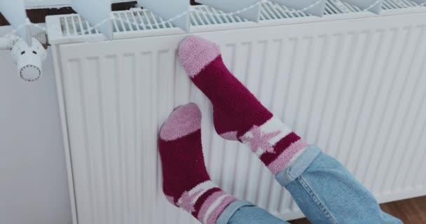 在公寓里寒冷的日子里 最好穿上暖和的毛袜 把你的脚抱在暖烘烘的散热器上 重新加热冻僵的脚 — 图库视频影像