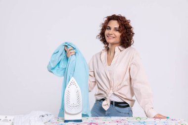 Demiri ütülemeden önce tatmin olmuş genç bir kız. Kız gömlekleri ütülemeyi seviyor. Evdeki günlük işler..