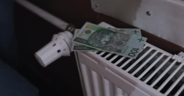 女性の手はラジエーターの上に紙幣を置く 銀行券の大宗派 各家庭の暖房エネルギー価格の上昇 — ストック動画