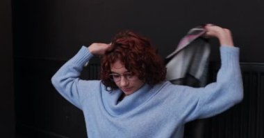 Mavi kazaklı bir kız kalın bir yün atkıyla kendini kapatıyor. Kışın, çalışan bir merkezi ısıtma sisteminin bakımı gereklidir..