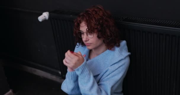 一个穿着厚毛衣的冷酷女人弯着腰坐在一个几乎没有暖气的散热器旁边 在冬天 重要的是要有一个高效的中央加热系统 — 图库视频影像