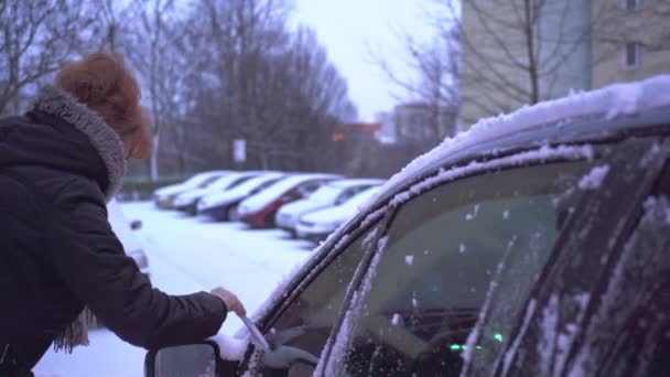 一个女人把雪从她车子的侧窗上抹去 冬天有很多雪的时候 那是个迷人的季节 汽车和车窗上的一层湿雪 — 图库视频影像