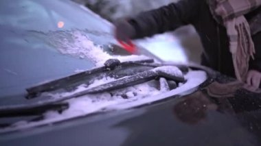 During the severe cold of winter, window scraping is inevitable. Winter season. Manual cleaning of the windshield of a passenger car.