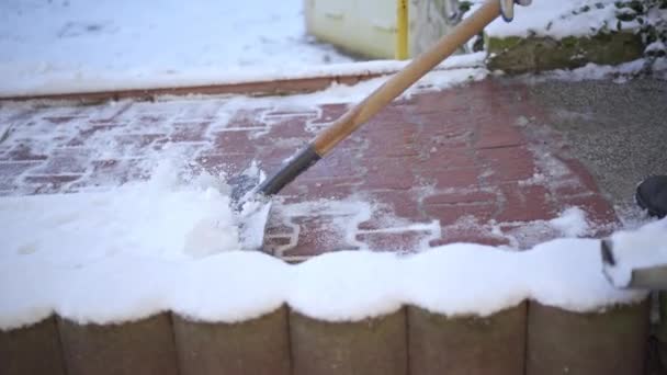 街の住宅開発の歩行者通路の雪の路地 圧縮された雪の脇に男がスクレープし 冬の朝の仕事 — ストック動画