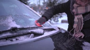 During the severe cold of winter, window scraping is inevitable. Winter season. Manual cleaning of the windshield of a passenger car.