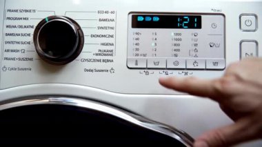 The man changes the number of rinses during one washing process on the set program - mix. He presses with his finger on the button with the rinse pictogram.