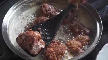 Homemade ways to fry chicken pieces in hot canola oil. A large stainless steel pan stands on the stove top.