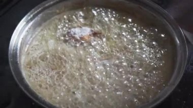 While boiling canola oil in a skillet, the cook puts breaded chicken pieces. Homemade ways to prepare meat for eating.