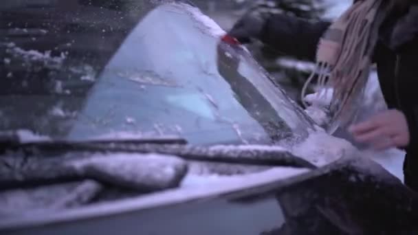 用冰冻的冰雪清洁汽车挡风玻璃 一个女人让她的车早上离开 多霜的早晨 — 图库视频影像