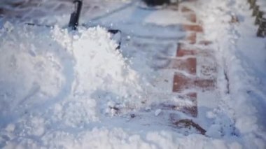 A blue-collar worker while performing his daily work during the winter season. Shoveling snow from paving stones and sidewalks and pedestrian alleys.