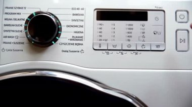 Çamaşır makinesindeki adam tokmağı kullanarak çamaşır yıkama programını ayarlıyor. Sıcaklığı, durulama sayısını, dönüş hızını ve kurutma derecesini ayarlayın