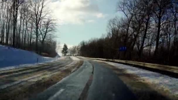 運転中に車のフロントガラスを介して見られるように街の外に雪の道 太陽がカメラに直接照りつける — ストック動画