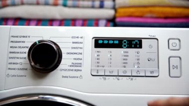Kontrol panelinde bir düğmeye basınca, adam kuruma derecesini ve programın süresini ayarlıyor. Ev yıkama ve kurutma ekipmanları.