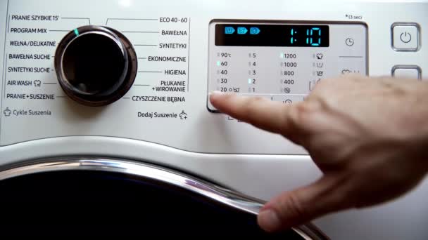 男は上のプログラムと洗濯の可能な温度範囲は何であるかを確認します ミックス 彼は体温計の絵文字でボタンを指をクリックします — ストック動画