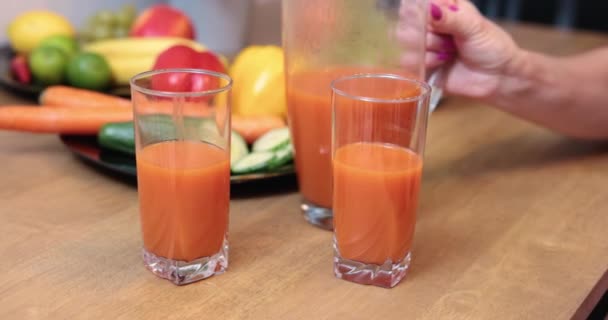 Két Pohár Narancslével Előtérben Háttérben Bolyhos Tányérok Gyümölcsökkel Zöldségekkel Szemüveg — Stock videók