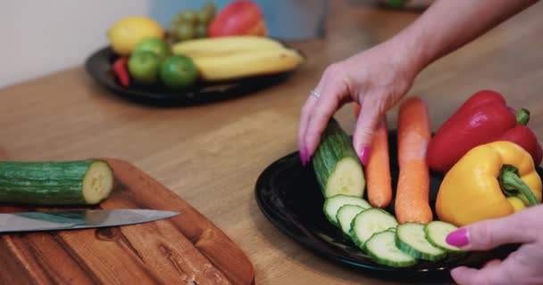ピンクの爪を持つ女性は 緑のキュウリ 赤と黄色のピーマンとニンジンなどの健康的な製品で構成された食事を準備します 食事は健康的に構成されています — ストック動画