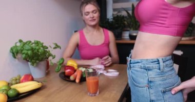 Kilo verme sonuçlarıyla övünen bir kadın göbeğini belli eder. Spor salonunda çalıştıktan sonra sıkı kaslar. Abdominal kilo kaybından dolayı pantolonu çok gevşek.