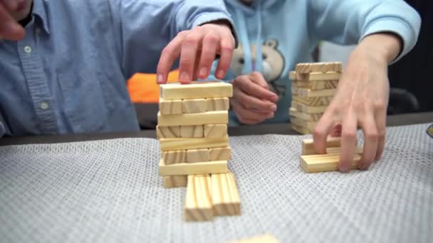 高い塔にブロックを積み上げながら クローズアップショット 家庭の快適さで一緒にゲームをプレイ 情熱的なゲームや木製のブロックで遊ぶ — ストック動画