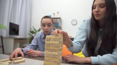 Playing with blocks of siblings in the living room. Sister and younger brother play together with blocks on the table.