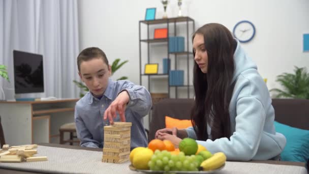 リビングルームで兄弟のブロックと遊ぶ 妹と弟はテーブルの上のブロックと一緒に遊ぶ — ストック動画