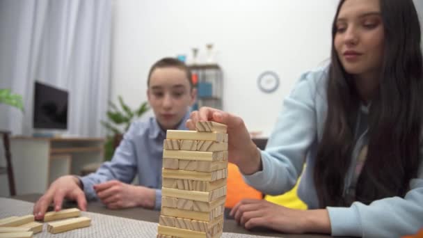 リビングルームで兄弟のブロックと遊ぶ 妹と弟はテーブルの上のブロックと一緒に遊ぶ — ストック動画