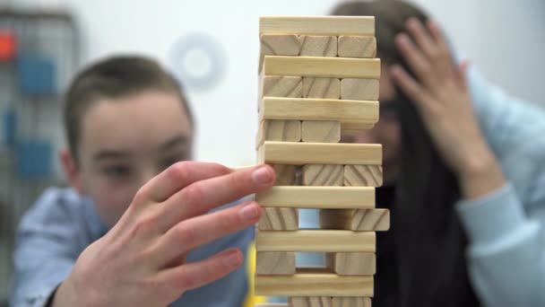 木製のブロックの塔のクローズアップショット 兄弟は大集中で一緒にアーケードゲームをプレイ — ストック動画