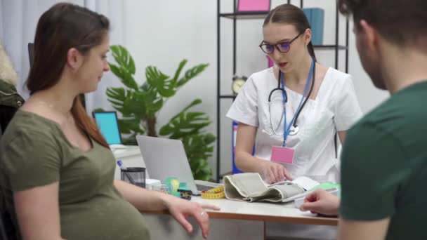 一个孕妇和她的丈夫坐在医生的办公室里 医生正在对她的病人进行血压检查 — 图库视频影像