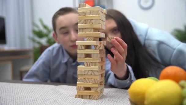木造の塔からブロックを取り出そうとしたが失敗し 建物全体が崩壊した 姉と弟がアーケードゲームで競い合う — ストック動画