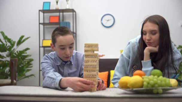 姉妹と弟は集中力と器用さを必要とする1つのゲームを一緒にプレイします 木造建築物の塔 — ストック動画