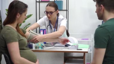 Periodic visit to the doctors office during the pregnancy period. After examining your blood pressure, the doctor removes the blood pressure monitor from your hand.