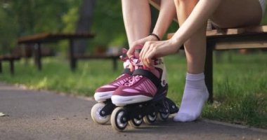 Bir kız sol ayağına paten takıyor. Kız beyaz çorap ve kısa yaz şortu giyiyor. Kadınların bacaklarına yakın çekim..