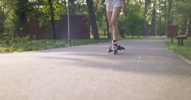 Parkta paten antrenmanı yapan bir atlet rampadan geçer. Kız yazlık spor kıyafeti giyiyor, şort ve kemer takıyor. Paten kayan kişinin bacaklarına yakın çekim